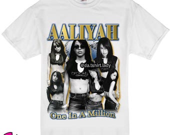 May include: White t-shirt with a gold graphic of Aaliyah and the text "One In A Million". The graphic features a collage of Aaliyah's images and musical notes.