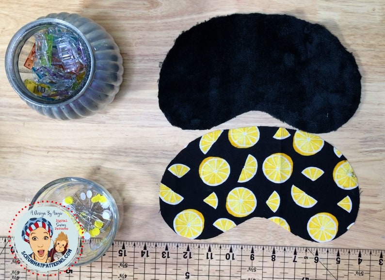May include: Two pieces of fabric for a sleep mask. One piece is black velvet and the other is black with a yellow lemon print. A ruler is in the bottom of the image.