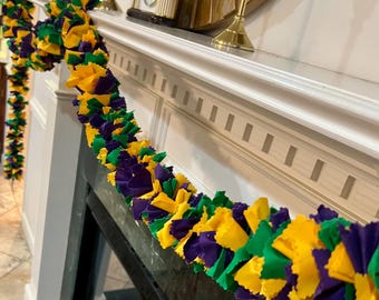 May include: A Mardi Gras garland made of purple, green, and gold fabric. The garland is made of fabric scraps that have been sewn together to create a festive look.