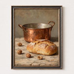 May include: A framed oil painting depicting a shiny copper pot with two handles positioned behind a round, golden-brown loaf of crusty bread. Four whole walnuts are scattered on the textured stone surface in front of the bread.