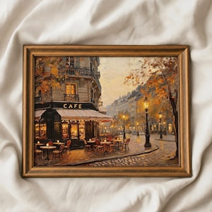 Pode incluir: Uma pintura a óleo numa moldura de madeira escura representando uma esquina parisiense com um café. A cena apresenta luzes quentes, mesas e cadeiras ao ar livre, ruas de paralelepípedos e árvores de outono com folhas douradas ao entardecer.