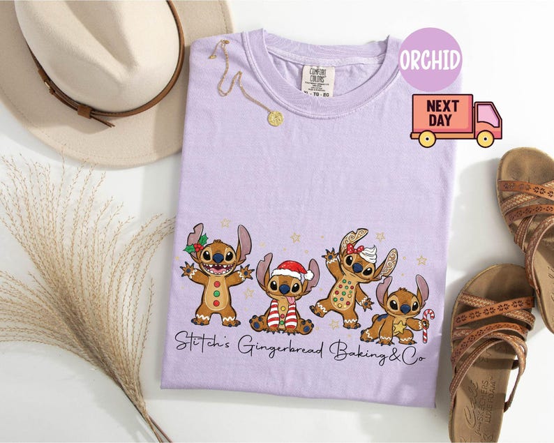 Puede incluir: Una camiseta de color lila claro con un dise&ntilde;o de Stitch con tem&aacute;tica de pan de jengibre. El gr&aacute;fico incluye cuatro personajes de Stitch vestidos como hombres de jengibre, con el texto "Stitch's Gingerbread Baking & Co." debajo. Tambi&eacute;n se ve un collar dorado y sandalias.