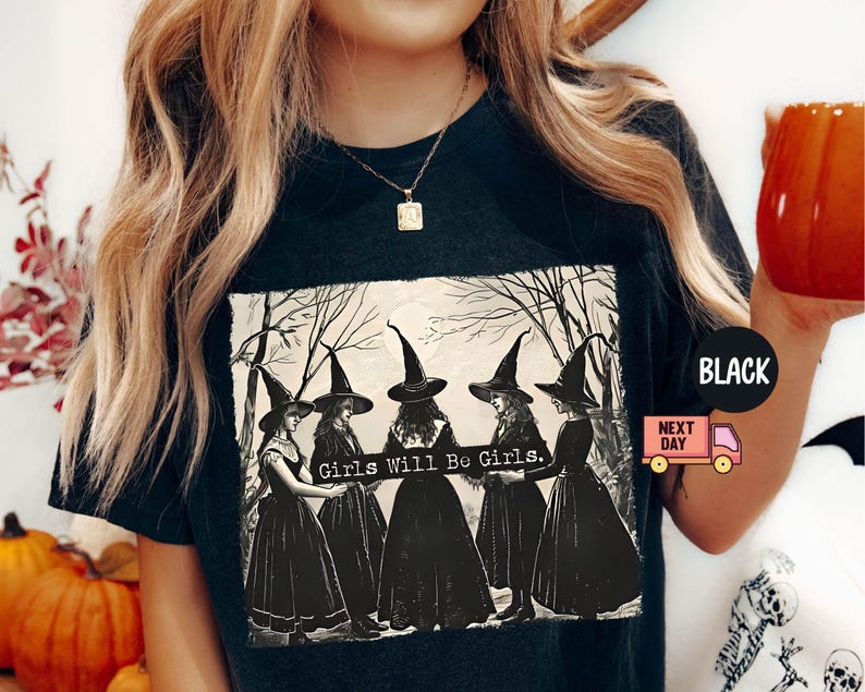 May include: Black t-shirt with a vintage illustration of four witches in black dresses and pointed hats. The text "Girls Will Be Girls." is printed on the shirt.