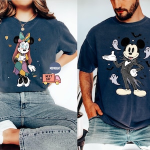 May include: Two navy blue t-shirts featuring Disney characters. One shirt displays Minnie Mouse in a patchwork dress, the other features Mickey Mouse in a pinstripe suit with ghosts and bats. Both shirts are short-sleeved.