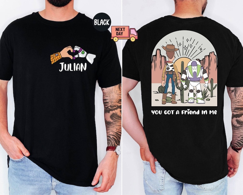 Pu&ograve; includere: Una t-shirt nera con una grafica frontale che mostra una mano umana e una mano robotica che formano un cuore sopra il nome JULIAN. La grafica sul retro mostra un cowboy e un ranger spaziale in un deserto con il testo YOU GOT A FRIEND IN ME.