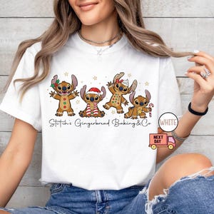 Puede incluir: Camiseta blanca con una ilustraci&oacute;n de dibujos animados de cuatro personajes de estilo pan de jengibre que se asemejan a Stitch, cada uno adornado con accesorios festivos. El texto "Stitch's Gingerbread Baking & Co" est&aacute; impreso debajo.