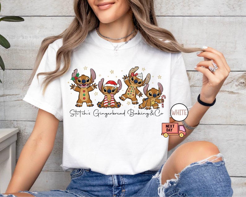 Puede incluir: Camiseta blanca con una ilustraci&oacute;n de dibujos animados de cuatro personajes de estilo pan de jengibre que se asemejan a Stitch, cada uno adornado con accesorios festivos. El texto "Stitch's Gingerbread Baking & Co" est&aacute; impreso debajo.