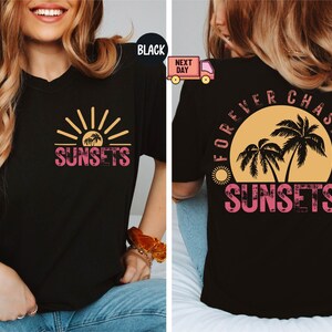 May include: Black t-shirt with a sunset graphic. The front features a sun and palm trees with the word "SUNSETS" in pink. The back of the shirt has a larger sunset design with the words "FOREVER CHASING SUNSETS".