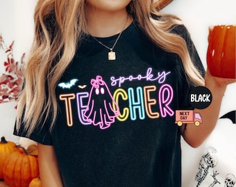 May include: Black t-shirt with a neon graphic that reads "spooky TEACHER" with a ghost and bat design. The shirt has a round neck and short sleeves. A black circle with the word "BLACK" is on the right side of the shirt.