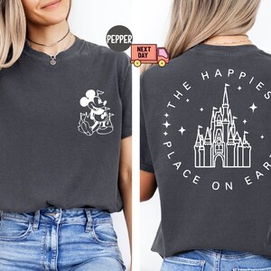 K&ouml;nnte beinhalten: Ein dunkelgraues T-Shirt mit einer wei&szlig;en Umrandung von Mickey Mouse auf der Vorderseite und einer wei&szlig;en Umrandung von Schloss Aschenputtel mit dem Text "The Happiest Place on Earth" auf der R&uuml;ckseite.
