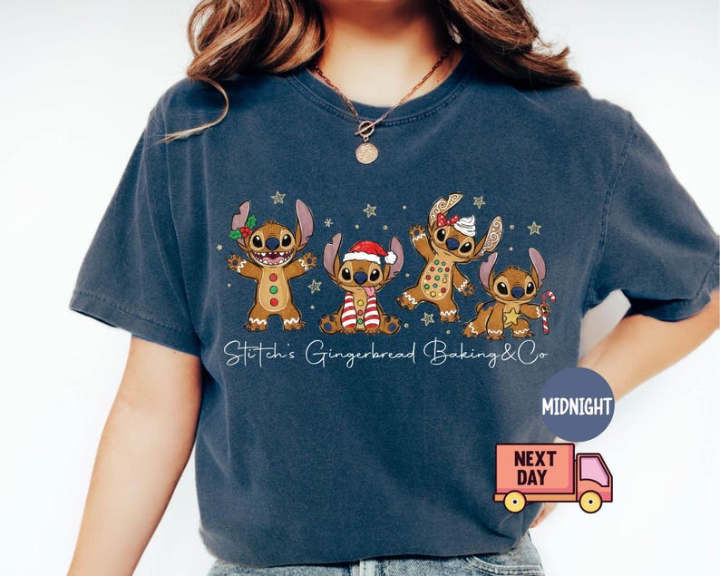 Puede incluir: Camiseta azul marino con cuatro personajes de dibujos animados con forma de pan de jengibre. Los personajes est&aacute;n decorados con detalles festivos como un gorro de Pap&aacute; Noel y un bast&oacute;n de caramelo. El texto "Stitch's Gingerbread Baking & Co" est&aacute; escrito en blanco.