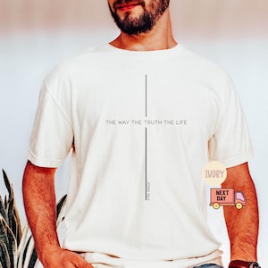 Puede incluir: Camiseta color crema con el texto "THE WAY THE TRUTH THE LIFE" y una l&iacute;nea vertical. Debajo de la l&iacute;nea est&aacute; el texto "JOHN 14:6". La camiseta es de manga corta y de estilo casual.