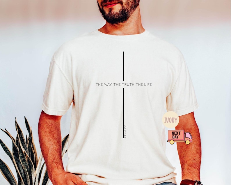 Puede incluir: Camiseta color crema con el texto "THE WAY THE TRUTH THE LIFE" y una l&iacute;nea vertical. Debajo de la l&iacute;nea est&aacute; el texto "JOHN 14:6". La camiseta es de manga corta y de estilo casual.