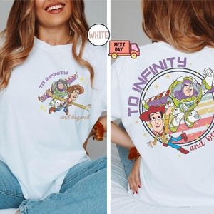 May include: White t-shirt with a purple and blue graphic of Woody and Buzz Lightyear from Toy Story. The graphic says "To Infinity and Beyond".