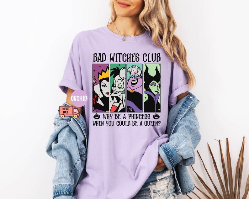 May include: A light purple t-shirt with the text "BAD WITCHES CLUB" and the phrase "WHY BE A PRINCESS WHEN YOU COULD BE A QUEEN?". The shirt features four cartoon images of Disney villains. The shirt is worn by a person.