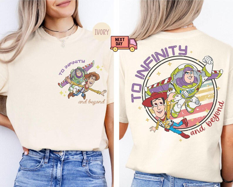 May include: A cream-colored t-shirt with a vintage-style graphic of Woody and Buzz Lightyear from Toy Story. The graphic features the text "To Infinity and Beyond" and a retro-style design with stars and stripes.