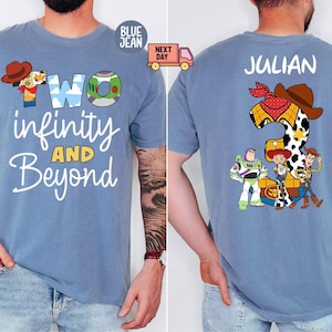 Puede incluir: Camiseta azul claro con el texto "TWO infinity AND Beyond" y un gráfico de dibujos animados. La parte trasera de la camiseta presenta el nombre "JULIAN" y el número 2 con personajes de Toy Story. La camiseta tiene cuello redondo.