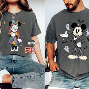 May include: Two gray t-shirts featuring Disney characters. One shirt displays Minnie Mouse in a patchwork dress with autumn leaves. The other shirt showcases Mickey Mouse dressed as Jack Skellington, surrounded by ghosts and bats.
