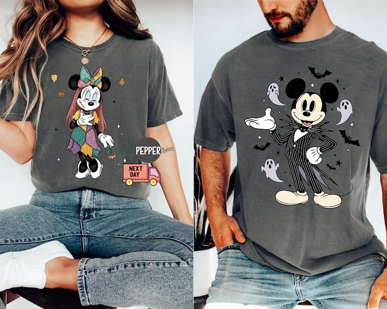 May include: Two gray t-shirts featuring Disney characters. One shirt displays Minnie Mouse in a patchwork dress with autumn leaves. The other shirt showcases Mickey Mouse dressed as Jack Skellington, surrounded by ghosts and bats.