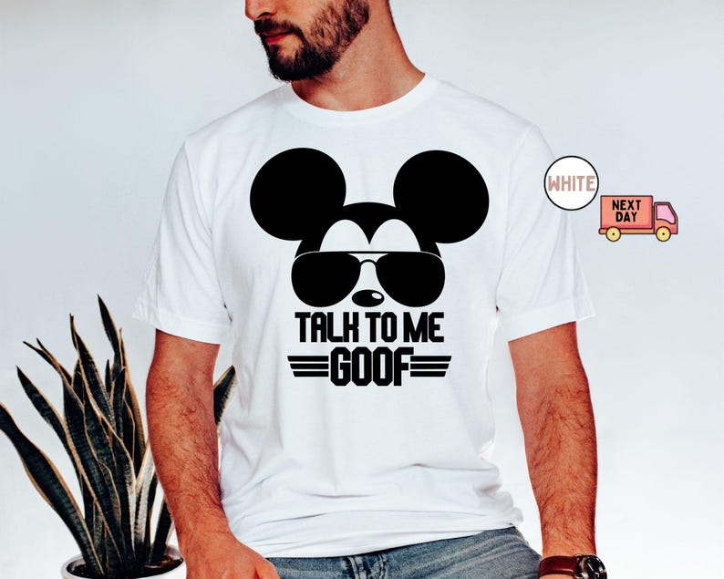 May include: A white short-sleeved t-shirt featuring a black graphic of a mouse head wearing sunglasses. Below the graphic, the text reads TALK TO ME GOOF in bold black capital letters, flanked by two horizontal lines on each side of the word GOOF.