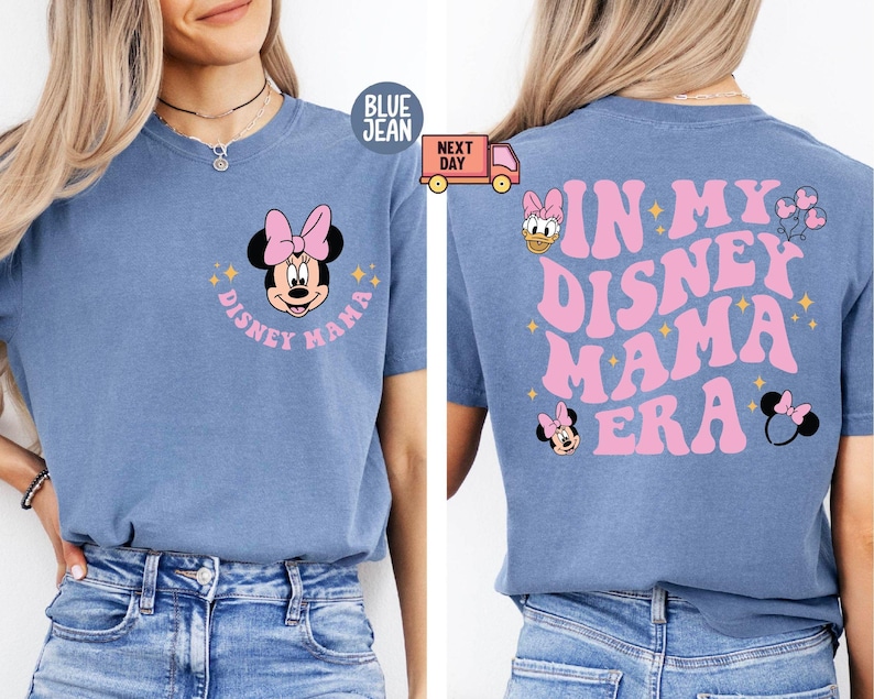 May include: Blue jean t-shirt featuring a Minnie Mouse graphic with a pink bow and the text "Disney Mama" on the front. The back of the shirt has the text "In My Disney Mama Era" in pink, along with additional Disney-themed graphics.