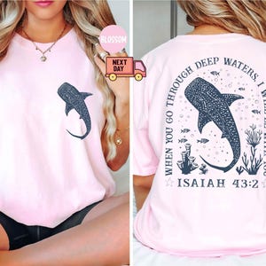 Op de afbeelding: Roze T-shirt met een walvishaai-afbeelding en de tekst "Wanneer je door diep water gaat, ben ik bij je. Jesaja 43:2"