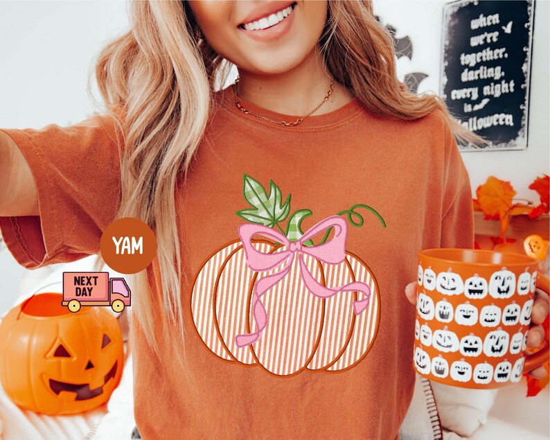 May include: Orange t-shirt with a pumpkin graphic, pink bow, and green leaves. An orange mug with jack-o'-lantern faces is held. A small orange pumpkin bucket is also visible. The text on the sign says "when we're together darling every night is halloween".