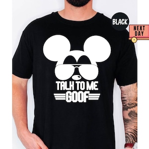 May include: A black short-sleeved t-shirt featuring a large white graphic of a mouse silhouette wearing sunglasses. Below the graphic, the text reads TALK TO ME GOOF in bold white capital letters, flanked by two horizontal lines on each side.