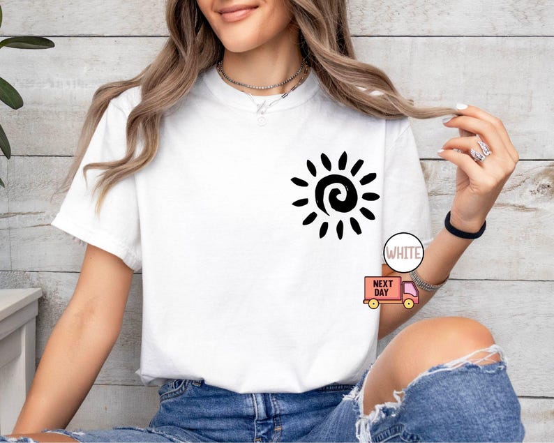 May include: White t-shirt with a black sun graphic on the front. The sun design features a spiral center and radiating lines. The shirt is paired with blue denim shorts. The text "WHITE" is visible on the image.
