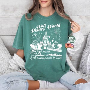 May include: Light green t-shirt with a white graphic of the Walt Disney World castle, Mickey Mouse, and other park elements. The text "Walt Disney World" and "The happiest place on earth" are printed on the shirt.