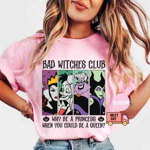 May include: Pink t-shirt with the text "BAD WITCHES CLUB" above a graphic of four cartoon villains. Below the graphic is the text "WHY BE A PRINCESS WHEN YOU COULD BE A QUEEN?" A small pumpkin graphic is on either side of the text.