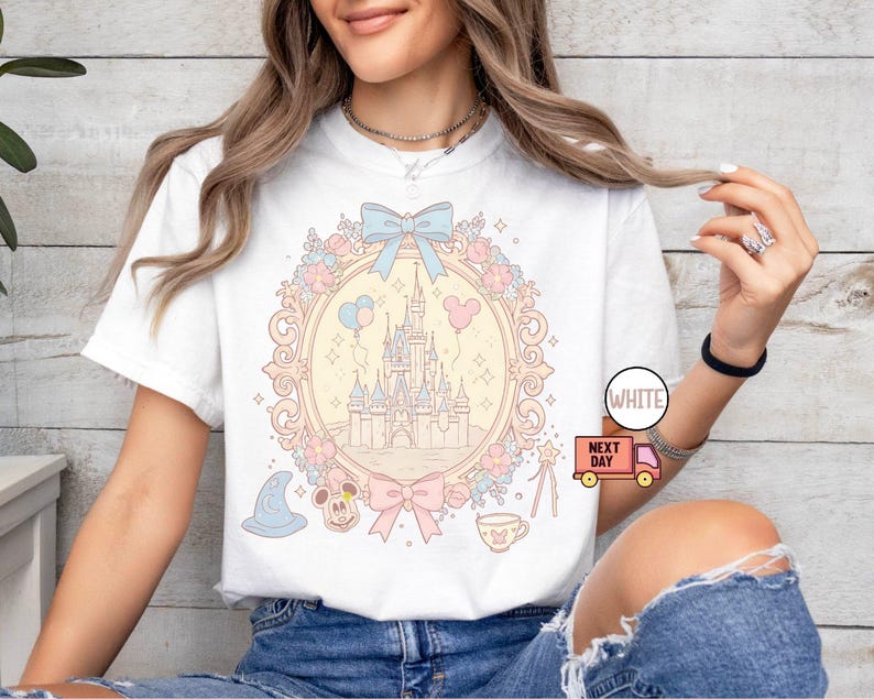 K&ouml;nnte beinhalten: Wei&szlig;es T-Shirt mit einer pastellrosa, blauen und gelben Illustration von Schloss Aschenputtel, Mickey Mouse und anderen Disney-Charakteren. Der Text "WHITE" und "NEXT DAY" ist auf dem Bild zu sehen.