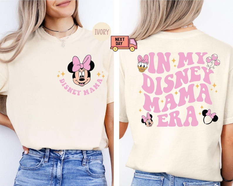 May include: Ivory-colored t-shirt featuring Minnie Mouse with a pink bow and the text "Disney Mama." The back of the shirt displays "In My Disney Mama Era" in pink, with additional Disney character graphics.