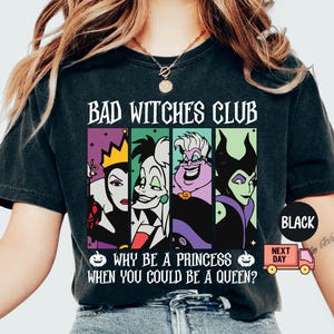 May include: Black t-shirt with the text "BAD WITCHES CLUB" and the phrase "WHY BE A PRINCESS WHEN YOU COULD BE A QUEEN?". The shirt features colorful portraits of four cartoon villains. A black circle with the word "BLACK" is on the sleeve.