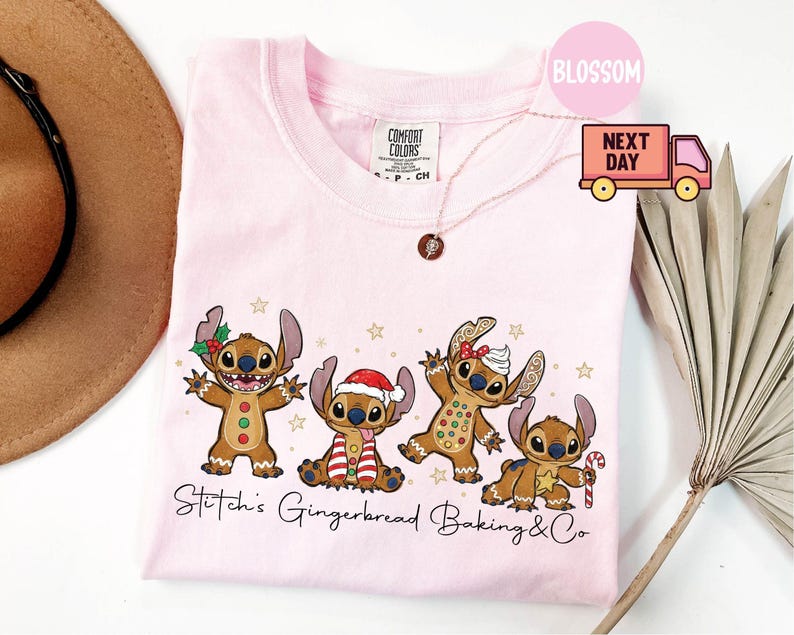 Puede incluir: Camiseta rosa claro con un dise&ntilde;o de cuatro personajes Stitch de jengibre con decoraciones navide&ntilde;as. El texto "Stitch's Gingerbread Baking & Co" est&aacute; impreso debajo. Cuello redondo.