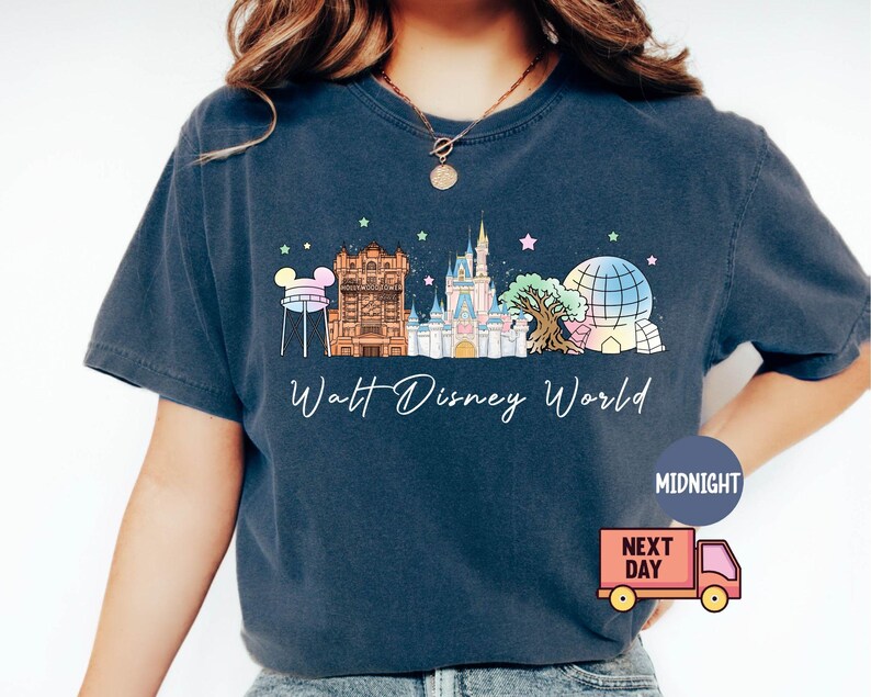 May include: Navy blue t-shirt featuring a colorful illustration of Walt Disney World landmarks, including Cinderella Castle and Spaceship Earth. The text "Walt Disney World" is written in a script font. The shirt has a relaxed fit.