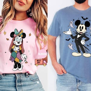 May include: Two t-shirts featuring Disney characters. One is pink with Minnie Mouse in a Halloween costume. The other is blue with Mickey Mouse dressed as Jack Skellington, surrounded by bats and ghosts.