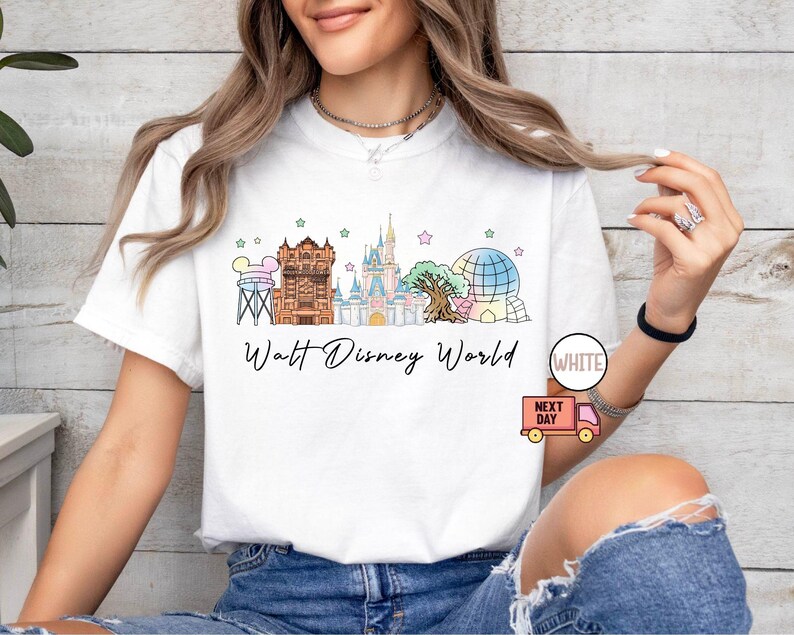 May include: White t-shirt featuring a colorful illustration of Walt Disney World landmarks, including Cinderella's castle and Spaceship Earth. The words "Walt Disney World" are written in a script font below the graphic.