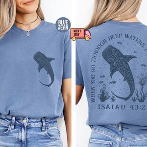 Op de afbeelding: Een blauw T-shirt met een walvishaai-afbeelding en de tekst "When you go through deep waters I will be with you Isaiah 43:2" op de achterkant.