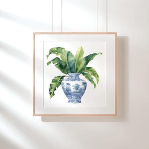 Puede incluir: Una pintura de acuarela de un jarr&oacute;n de porcelana azul y blanco con una planta verde frondosa en su interior. El jarr&oacute;n tiene un dise&ntilde;o floral y la planta tiene hojas grandes y tropicales.
