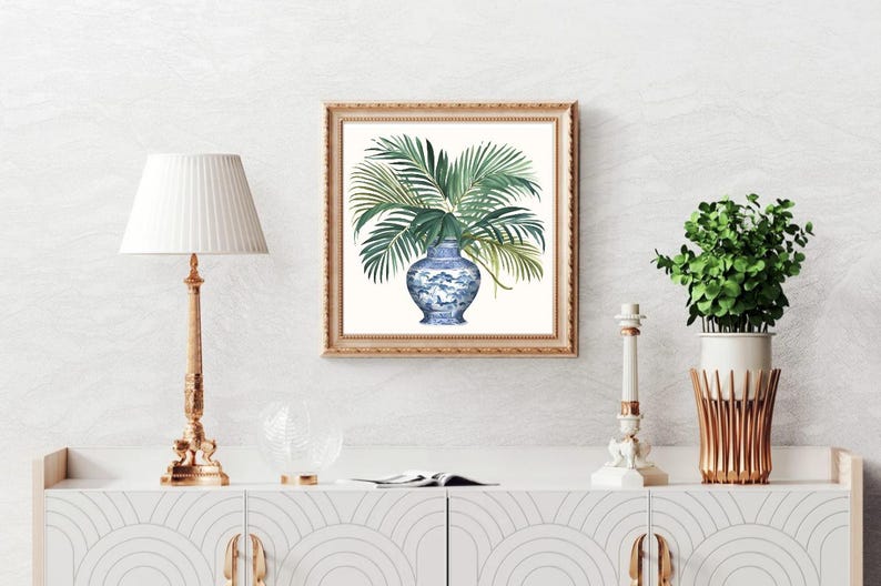 Puede incluir: Una pintura de acuarela de un jarr&oacute;n de porcelana azul y blanco lleno de hojas de palma verdes. El jarr&oacute;n est&aacute; decorado con un patr&oacute;n floral. La pintura est&aacute; enmarcada en un marco dorado.