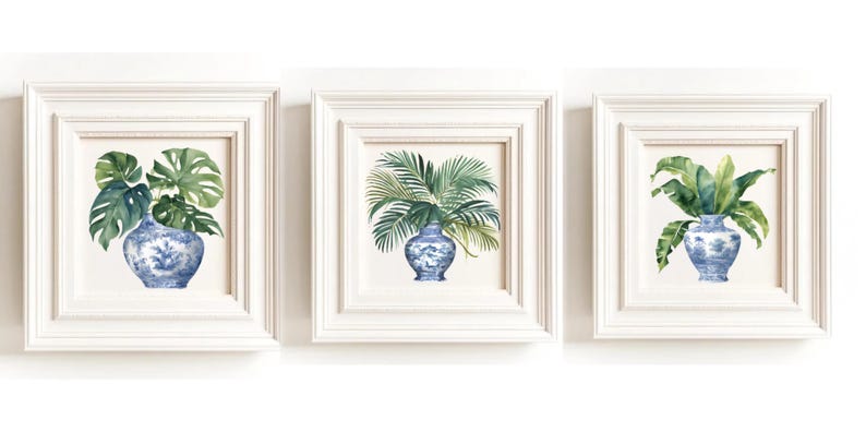 Puede incluir: Tres impresiones enmarcadas blancas con jarrones de porcelana azul y blanco llenos de hojas tropicales verdes. Las impresiones est&aacute;n dispuestas en una fila.