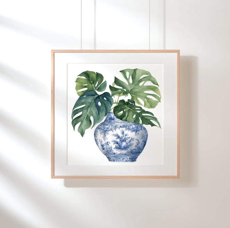 Puede incluir: Una pintura de acuarela enmarcada de un jarr&oacute;n de porcelana azul y blanco con hojas verdes de monstera.
