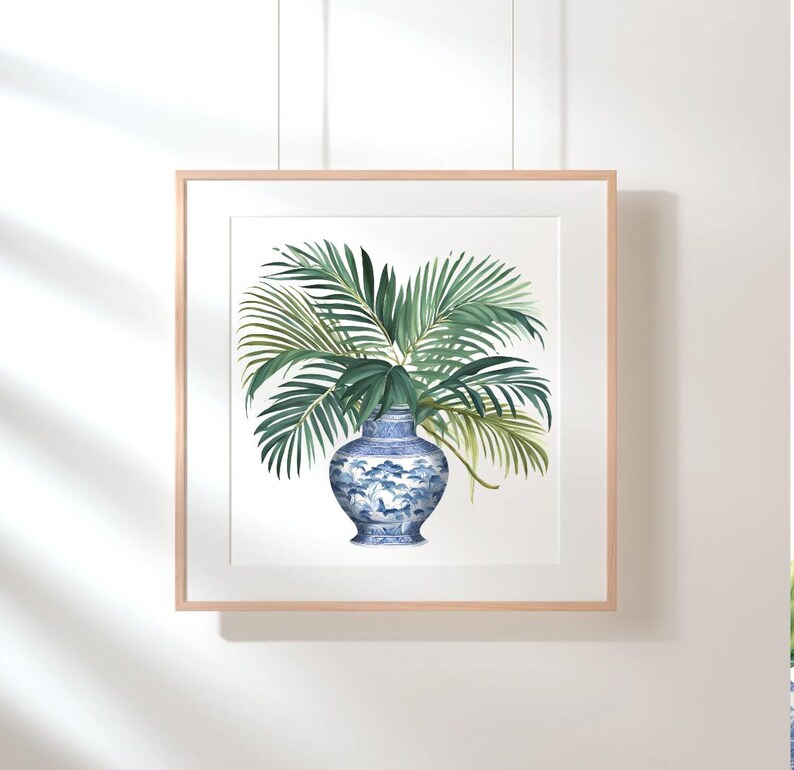 Puede incluir: Una impresi&oacute;n enmarcada de un jarr&oacute;n de porcelana azul y blanco con un arreglo de hojas de palmera verdes.