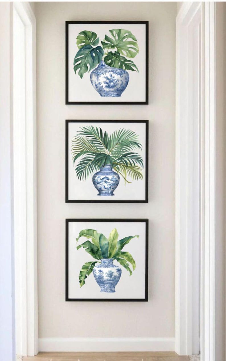 Puede incluir: Tres acuarelas enmarcadas de plantas tropicales en jarrones de porcelana azul y blanco. La pintura superior presenta hojas de monstera, la pintura del medio presenta frondas de palmeras y la pintura inferior presenta un helecho.