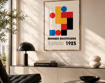 May include: A framed wall poster featuring a Bauhaus Ausstellung 1925 graphic with geometric shapes in red, yellow, blue, and black on a white background, displayed in a room with a black lamp, a black chair, and a marble coffee table.