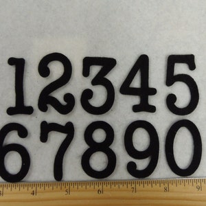 May include: Black felt numbers 1 through 0 in a whimsical font style. The numbers are approximately 2 inches tall.