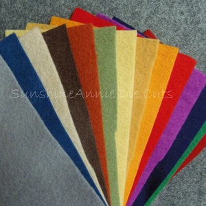 May include: A variety pack of felt sheets in a rainbow of colors, including gray, blue, beige, brown, orange, green, yellow, orange, red, purple, navy, green, and red. The felt sheets are arranged in a fan shape, with the gray sheet at the bottom and the red sheet at the top. The text "Sunshine Annie Die Cuts" is visible in the center of the image.
