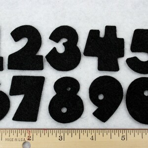 May include: Ten black felt numbers, 1 through 10, with a hole in each number. The numbers are arranged in two rows, with the first row containing numbers 1 through 5 and the second row containing numbers 6 through 10.
