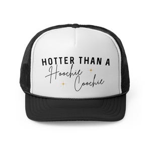May include: Black and white trucker hat. The white front panel displays the text "HOTTER THAN A Hoochie Coochie" in black script. The hat has a black brim and a mesh back.